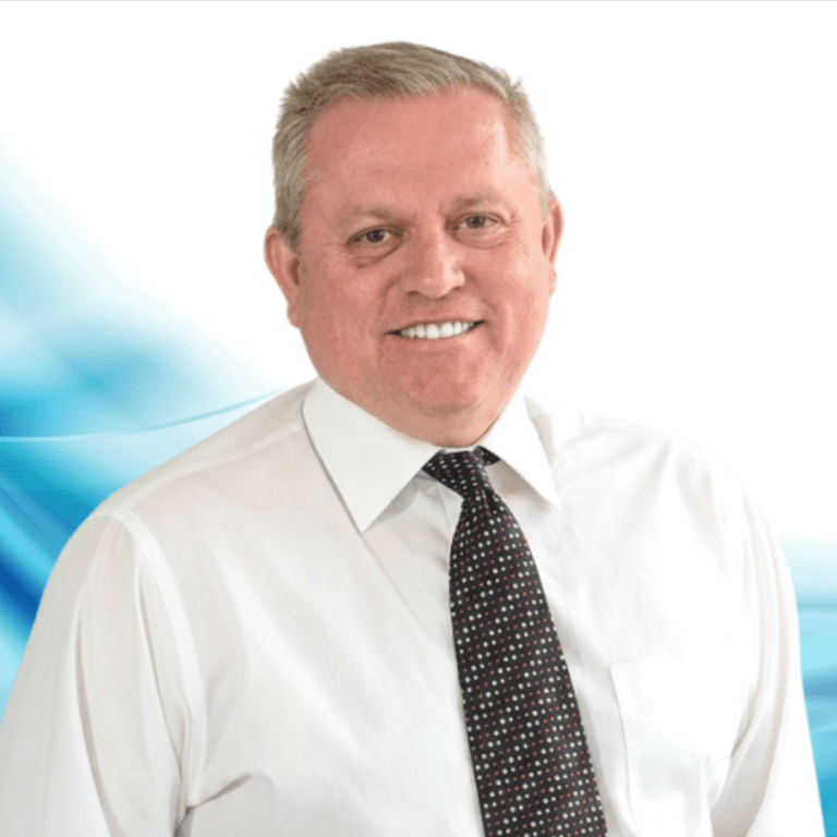 Professional headshot: smiling middle-aged man in a white shirt and patterned tie with a blue abstract background.
