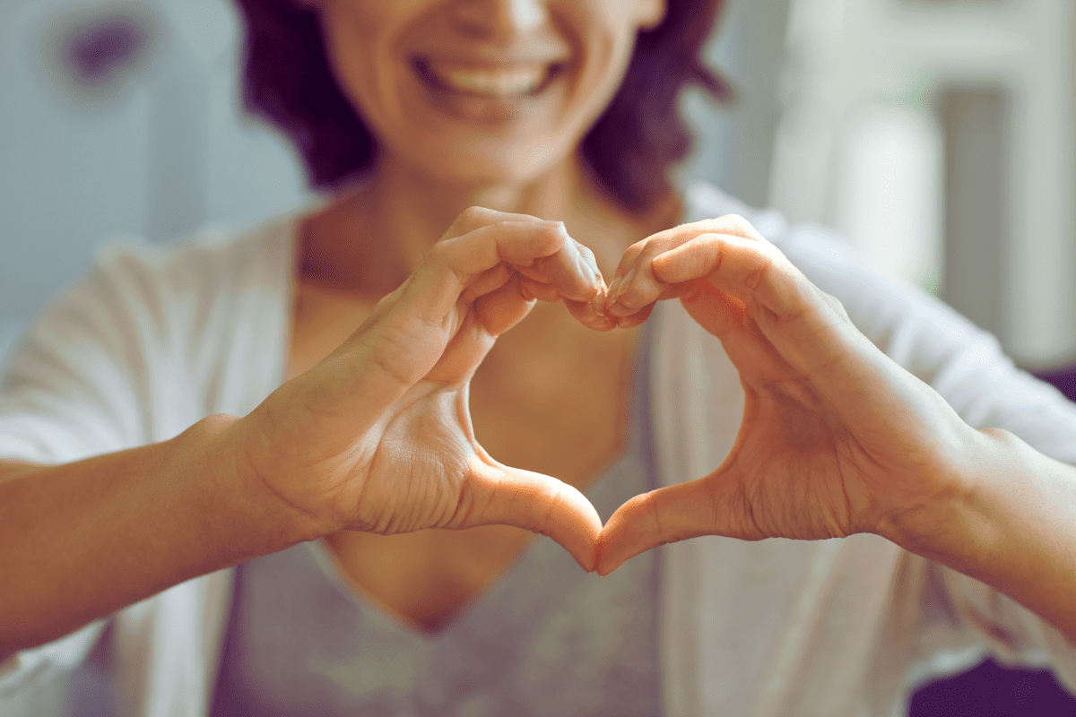 woman making heart shape with hands to celebrate American Heart Month