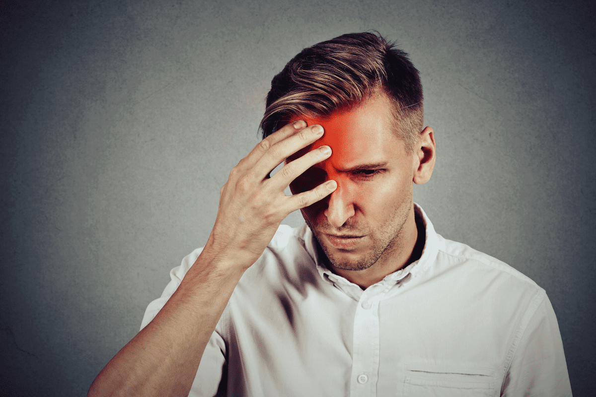 man with new daily persistent headache touching forehead in pain