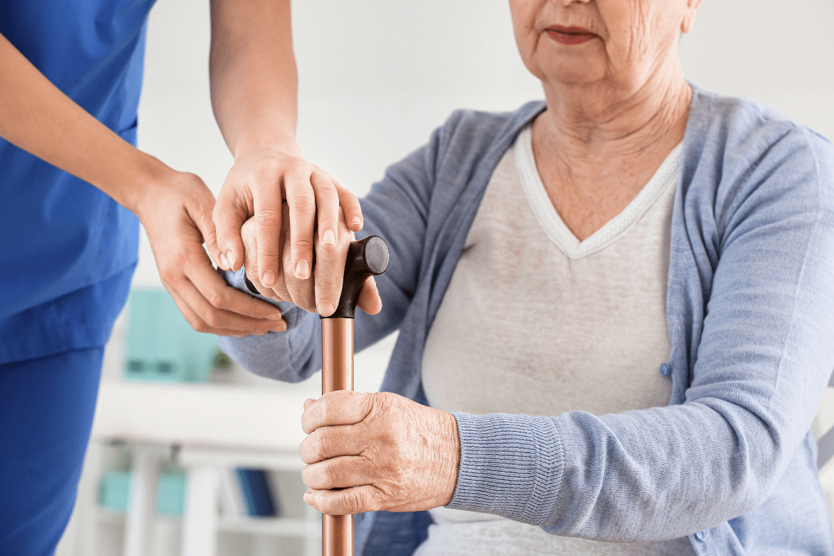 woman with parkinson's disease being shown how to use cane for walking