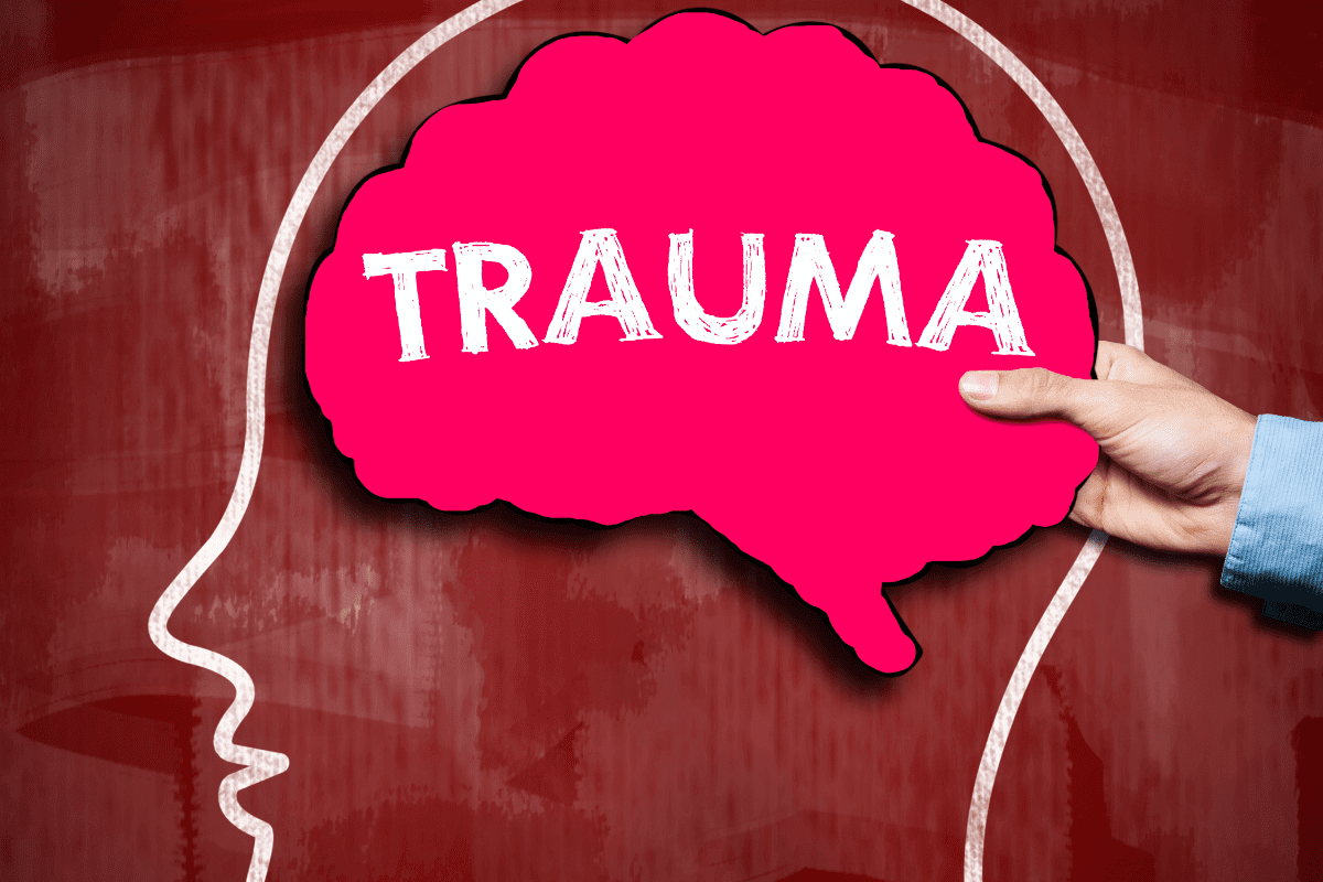 graphic depicting a pink cutout of a brain with "trauma" written in chalk